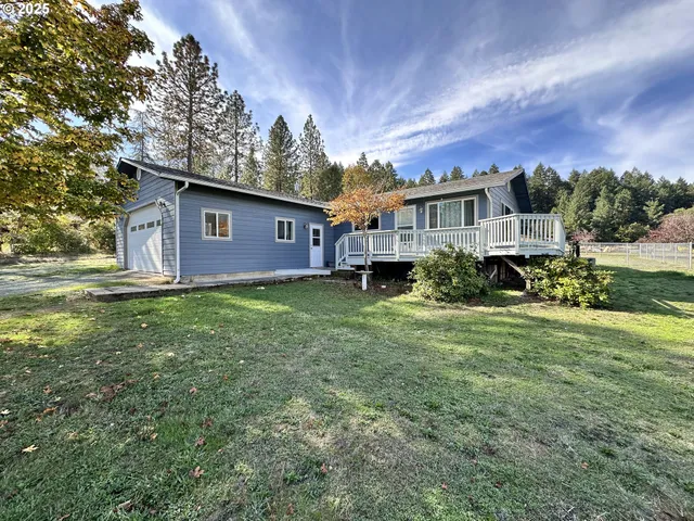 a view of a house with a big yard plants and large trees