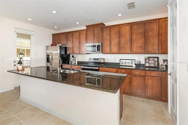 a kitchen with stainless steel appliances granite countertop a stove a sink a refrigerator a sink and dishwasher with wooden cabinets