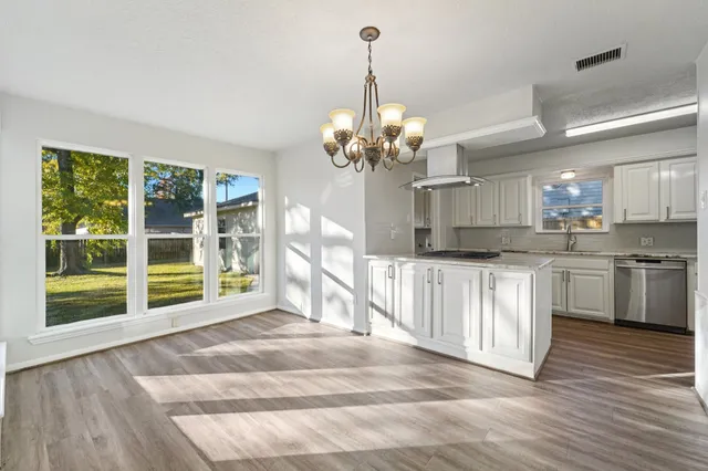 a view of a kitchen with granite countertop a large window cabinets and stainless steel appliances