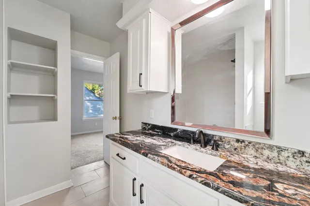 a bathroom with a granite countertop sink and a mirror
