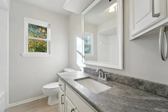 a bathroom with a granite countertop sink toilet and mirror