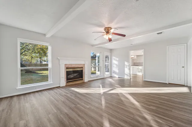 a view of an empty room with a fireplace and wooden floor