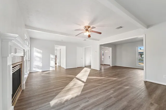 a view of an empty room with wooden floor and a fireplace