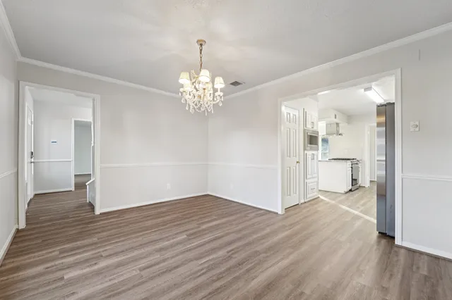 a view of a hallway with wooden floor and a chandelier