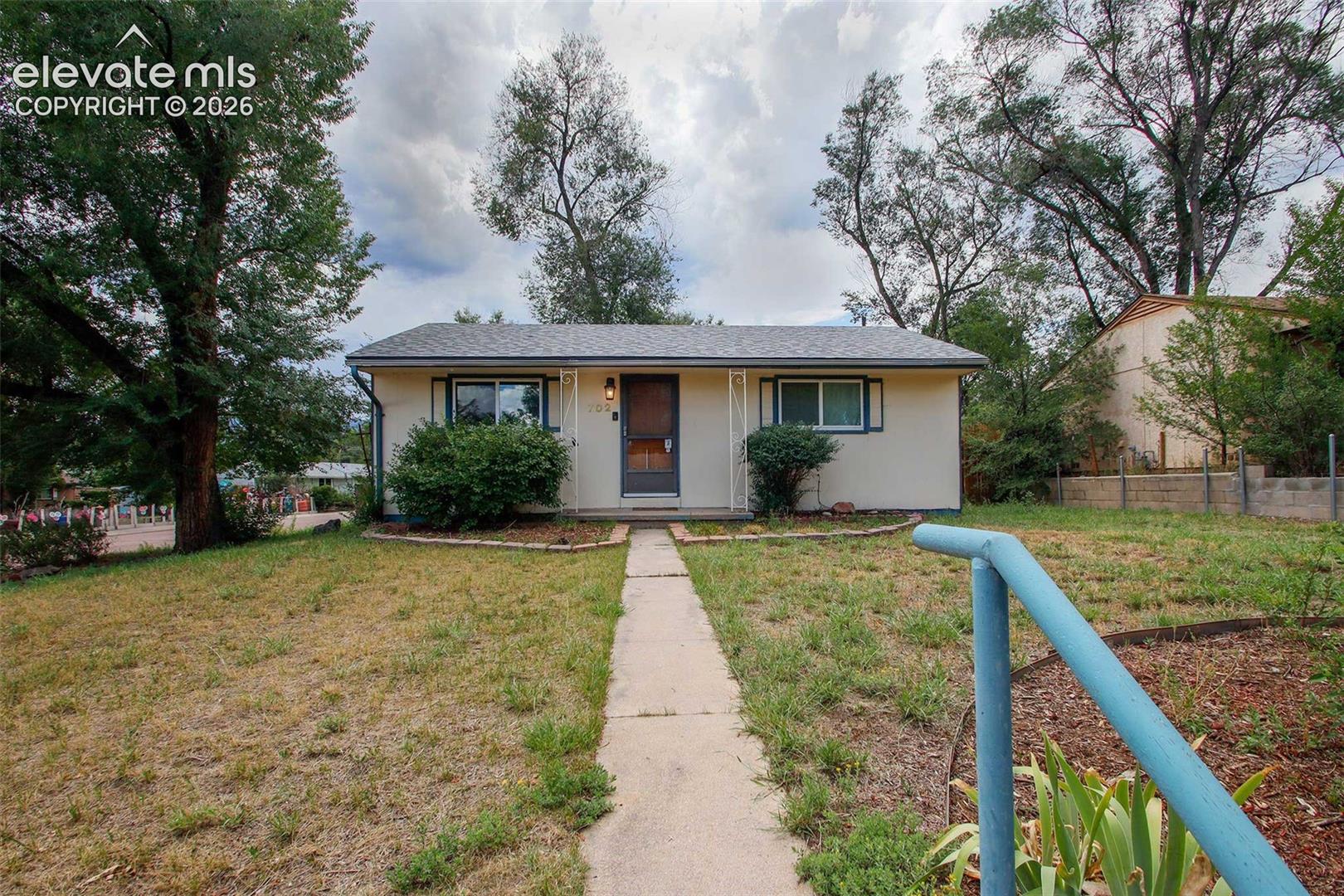 702 Erie Road Colorado Springs, CO 80910 - Photo 18 of 19 Single-story exterior with a light-toned facade, dark-framed windows, and a front entry door with an overhead light fixture