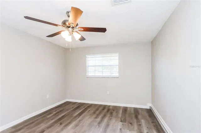 an empty room with a window and a fan