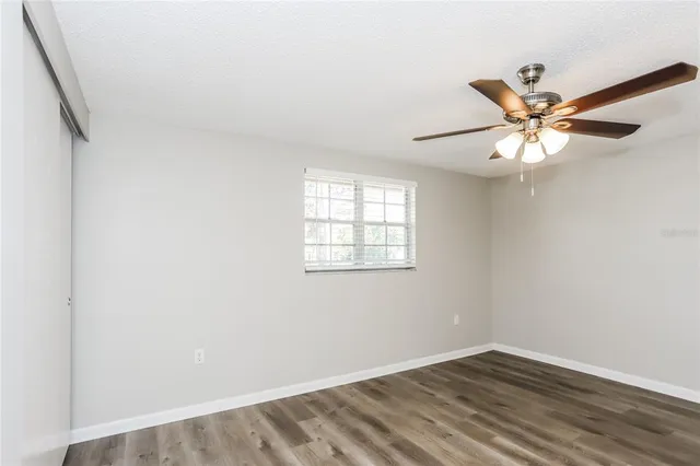 an empty room with a window and a fan
