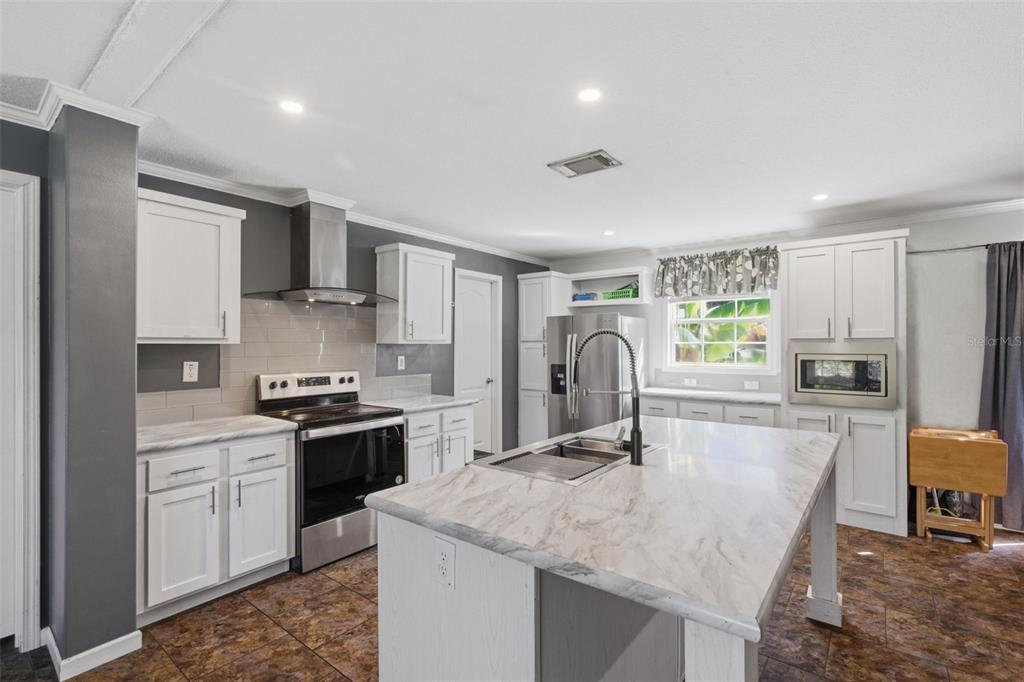 5022 Carol Drive Wesley Chapel, FL 33543 - Photo 6 of 25 a kitchen with stainless steel appliances granite countertop a sink stove top oven and refrigerator