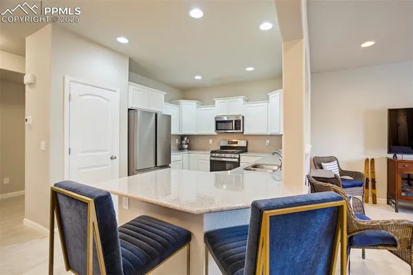 a kitchen with stainless steel appliances a refrigerator a stove a sink cabinets and a dining table