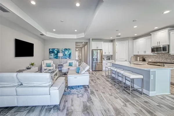 a living room with stainless steel appliances furniture a flat screen tv and a view of kitchen