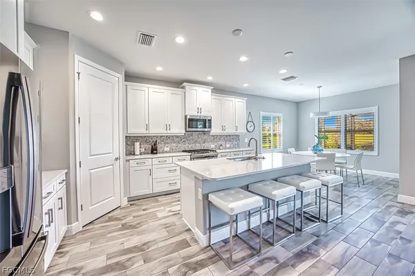 a large white kitchen with granite countertop a stove a sink a dining table and chairs