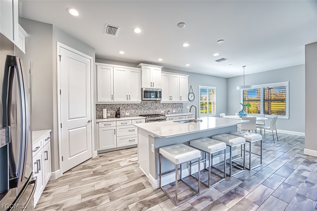 2925 Willow Ridge Court Fort Myers, FL 33905 - Photo 33 of 50 a large white kitchen with granite countertop a stove a sink a dining table and chairs