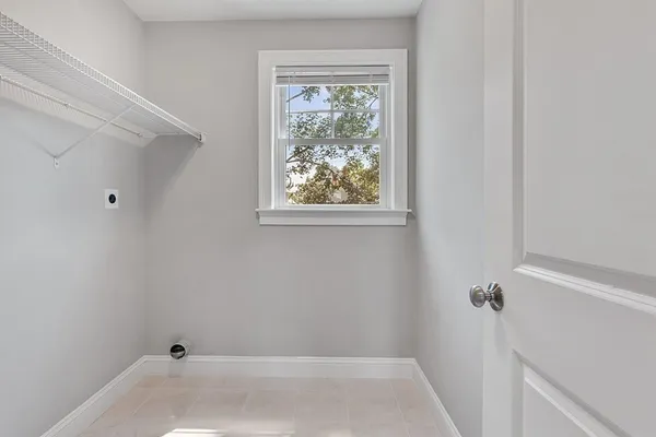 a view of an empty room with wooden floor and fan