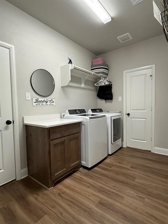 F1201 Sanger Drive Springtown, TX 76082 - Photo 8 of 11 Washroom featuring dark wood-type flooring, washer and clothes dryer, cabinet space, and a textured ceiling