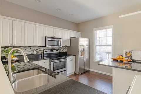 a kitchen with granite countertop white cabinets and white appliances