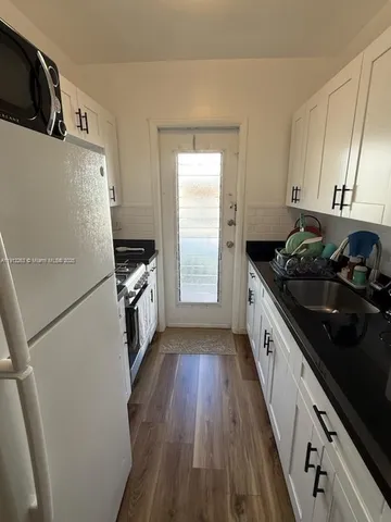 a kitchen with granite countertop a refrigerator a sink dishwasher stove and oven with wooden floor