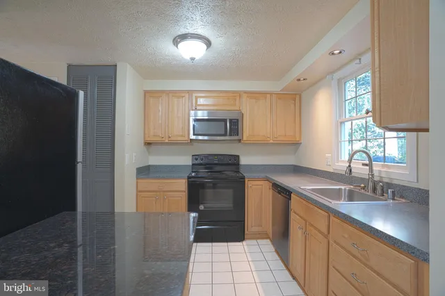 a kitchen with granite countertop a refrigerator and a sink