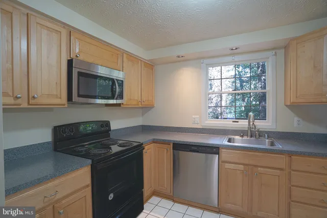 a kitchen with granite countertop a sink a stove a microwave and wooden cabinets