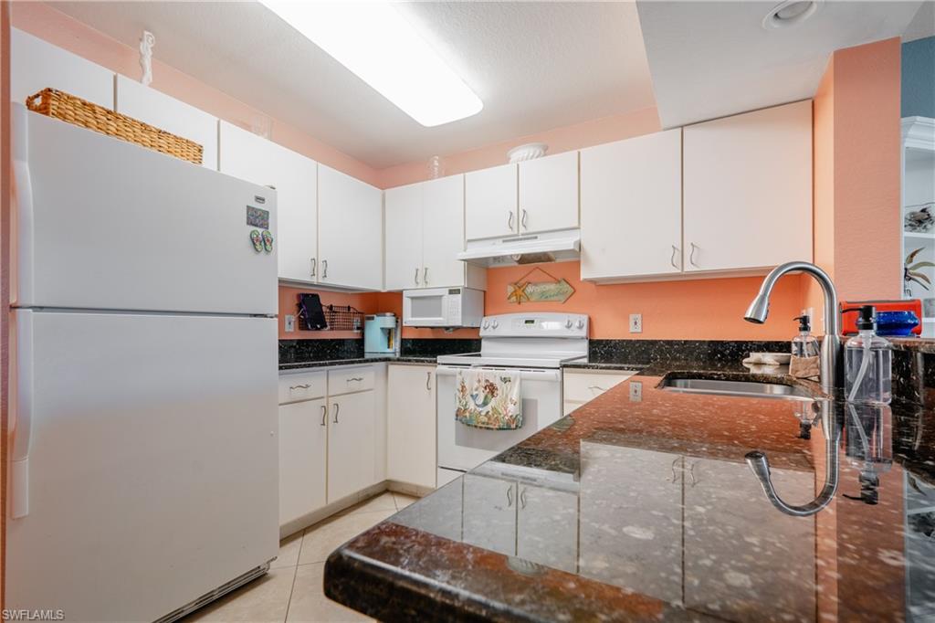 8264 Key Royal Circle, Unit 813 Naples, FL 34119 - Photo 8 of 21 a kitchen with a refrigerator and white cabinets