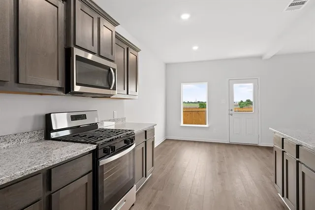 a kitchen with stainless steel appliances granite countertop a stove a sink and a microwave