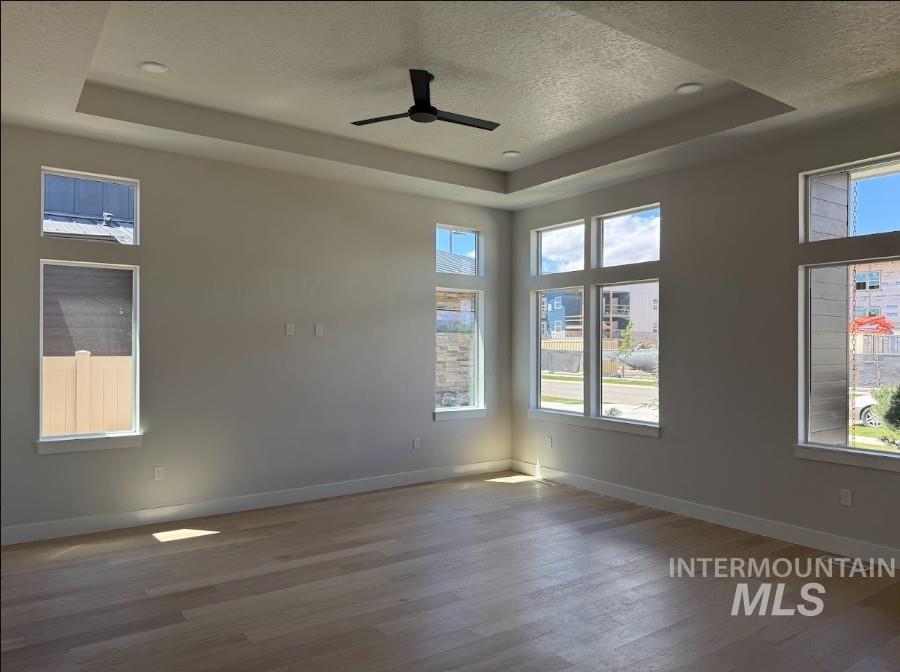 665 West Wrangler Street Meridian, ID 83646 - Photo 4 of 18 Spacious room featuring light wood-finish flooring, a tray ceiling with recessed lighting and a ceiling fan, and multiple large windows providing ample illumination