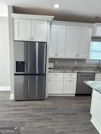 a kitchen with granite countertop a refrigerator sink and cabinets