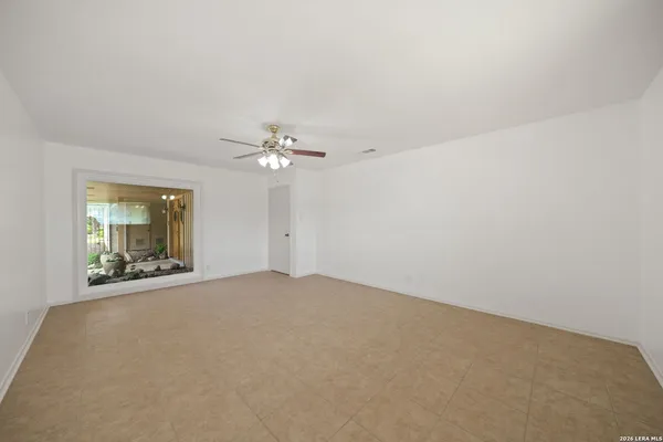 an empty room with windows and chandelier fan