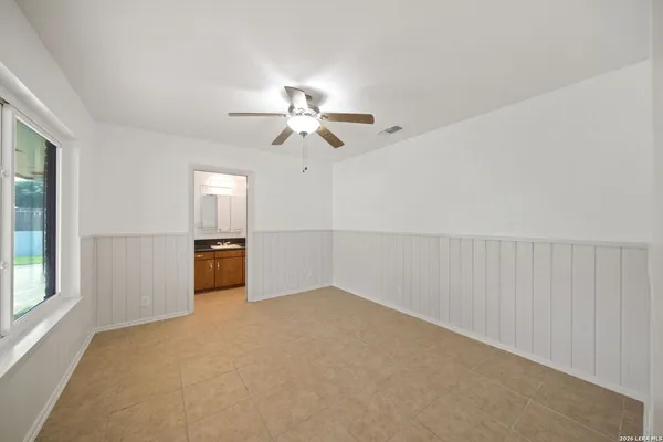 an empty room with chandelier fan and windows