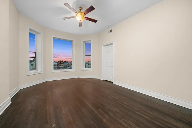 an empty room with windows and ceiling fan