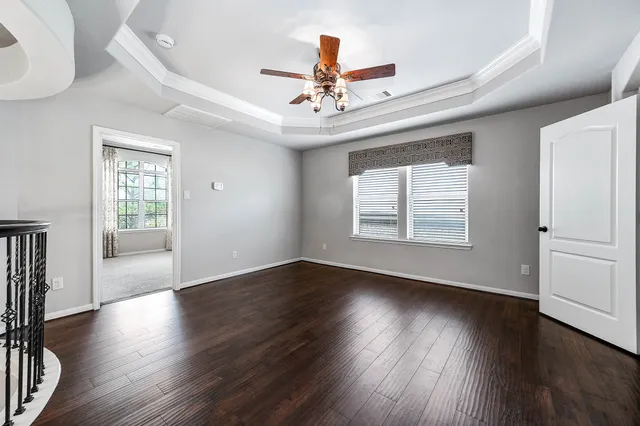 an empty room with wooden floor chandelier fan and windows