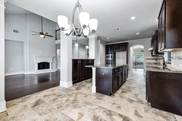 a large kitchen with stainless steel appliances kitchen island granite countertop a large counter top and wooden floors