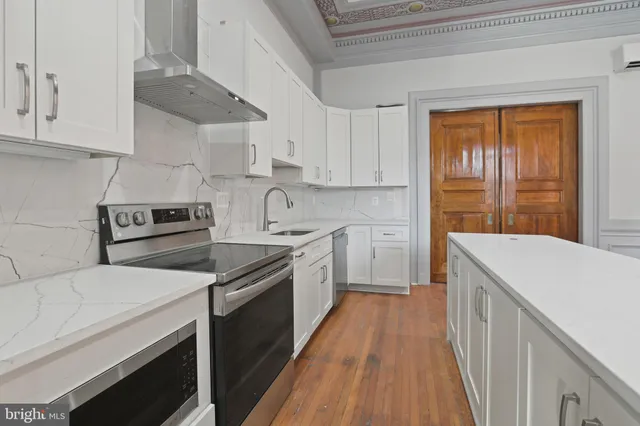 a kitchen with kitchen island wooden floors white appliances and cabinets