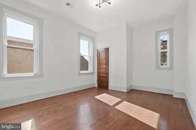 an empty room with windows closet and chandelier fan