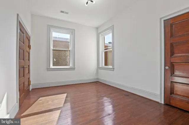 an empty room with wooden floor and windows