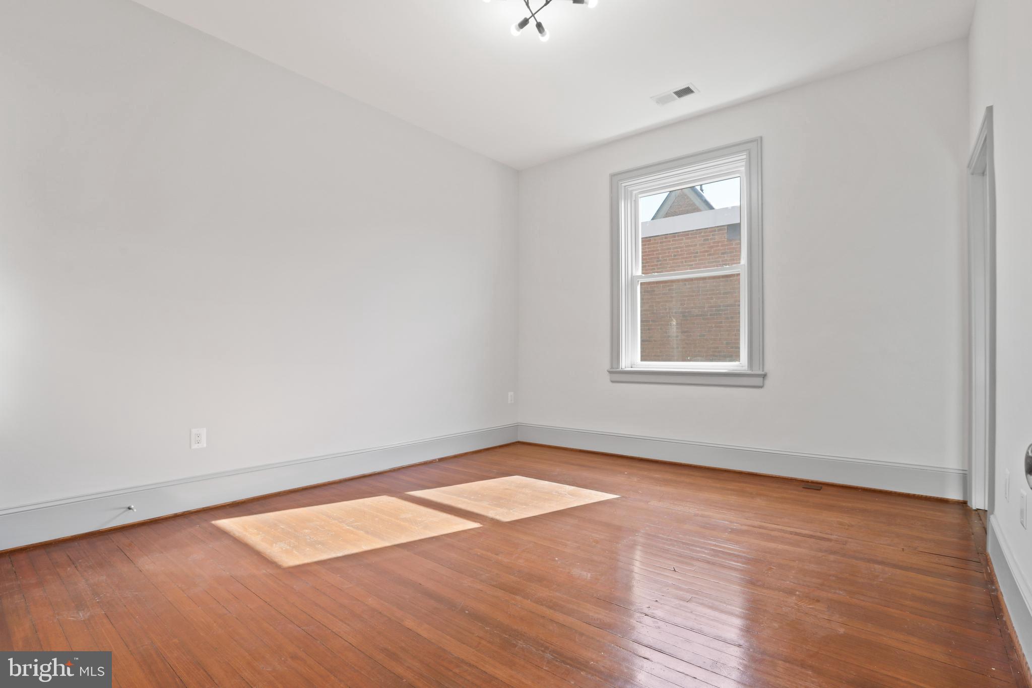 812 Park Avenue, Unit 2FR Baltimore, MD 21201 - Photo 27 of 30 an empty room with wooden floor and windows