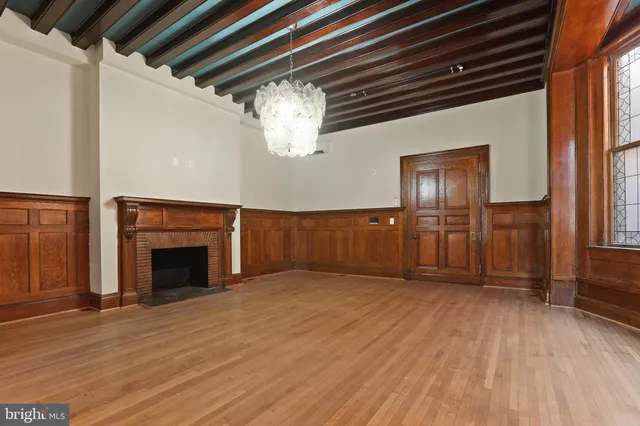 an empty room with wooden floor fireplace and windows
