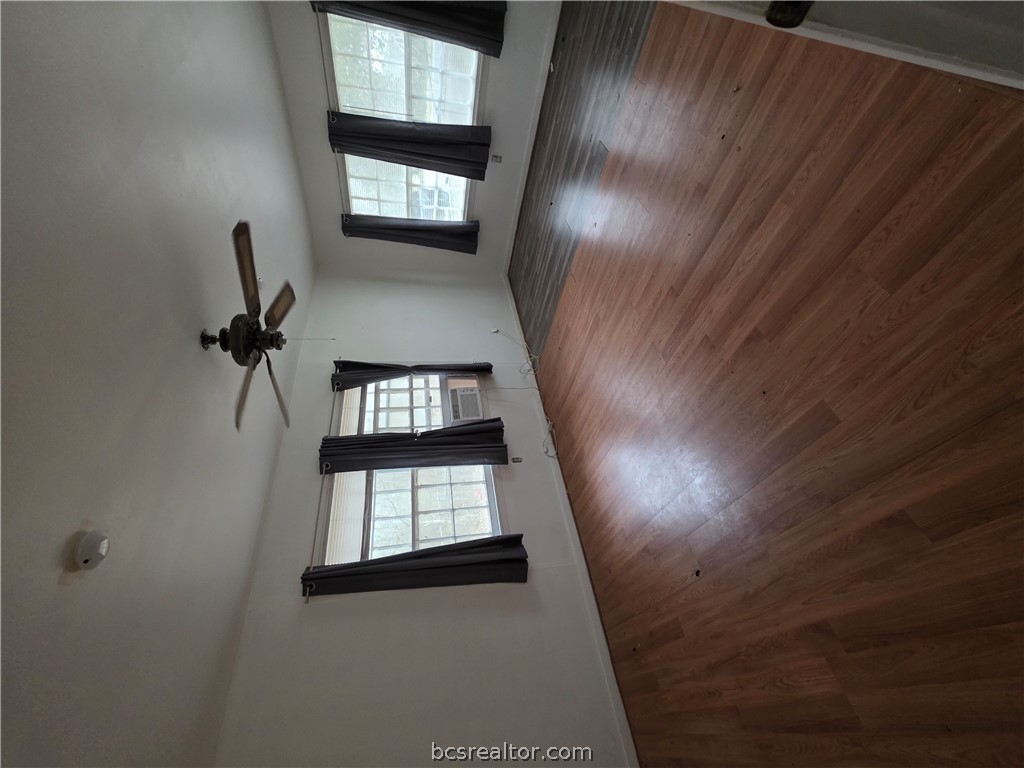 3815 Luza Lane Bryan, TX 77807 - Photo 3 of 18 a view of an empty room with wooden floor ceiling fan and windows