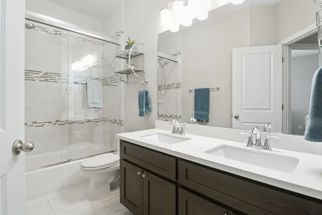a bathroom with a double vanity sink toilet mirror and shower