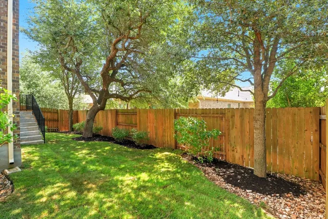 a view of a backyard with large trees and a barn in it