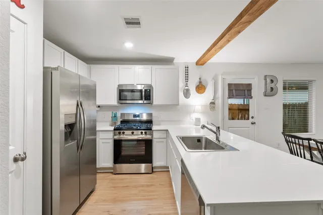 a kitchen with a refrigerator a stove top oven a sink dishwasher and wooden floor