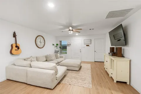 a living room with furniture a clock and a flat screen tv