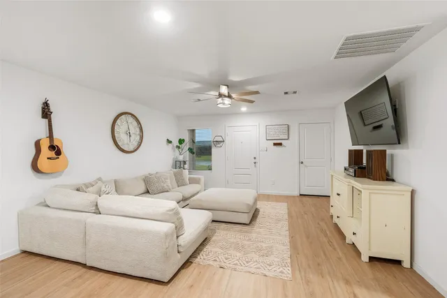 a living room with furniture a clock and a flat screen tv