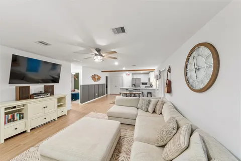 a living room with furniture a flat screen tv and kitchen view