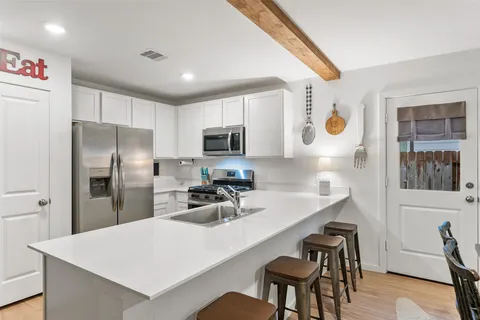 a kitchen with a refrigerator a stove a sink a dining table and chairs