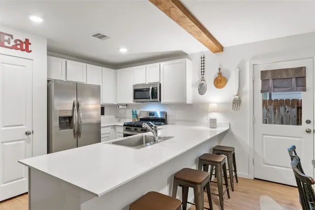 a kitchen with a refrigerator a stove a sink a dining table and chairs