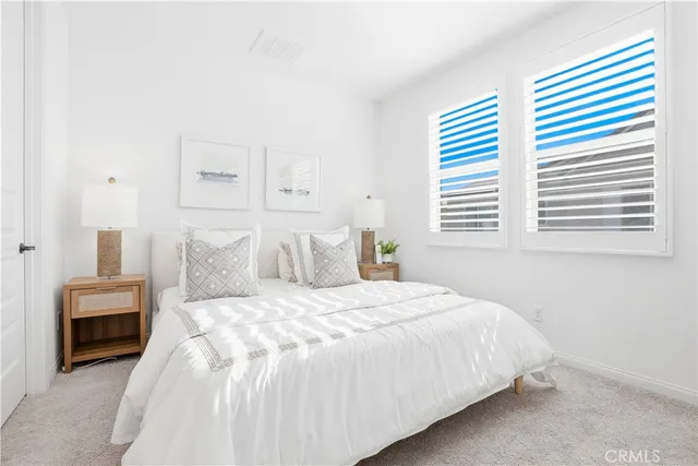 a large white bed sitting in a bedroom next to a window