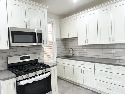a kitchen with white cabinets and appliances
