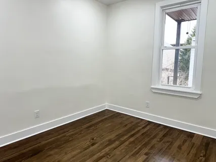 a view of a room that has wooden floor and windows