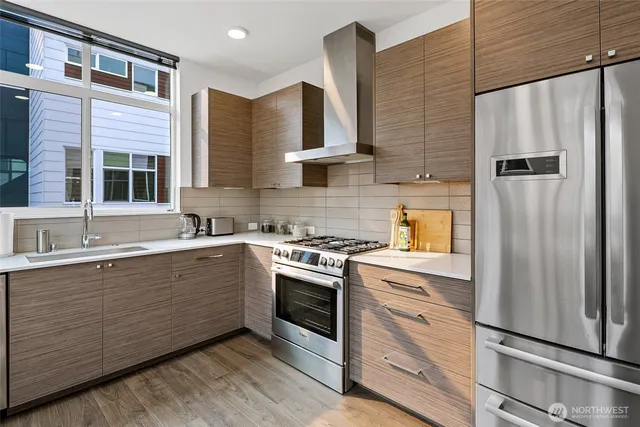 a kitchen with stainless steel appliances white cabinets and wooden floor