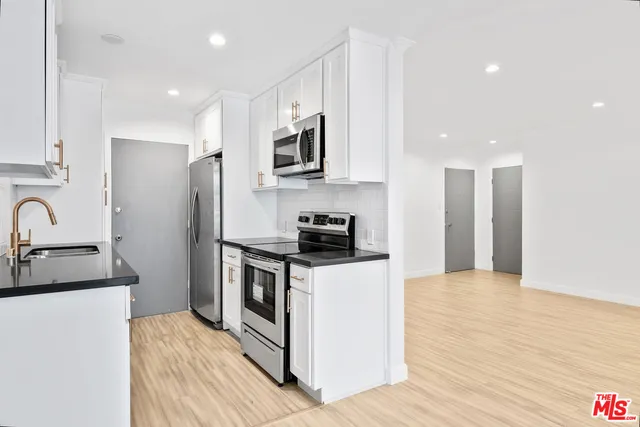 a kitchen with stainless steel appliances granite countertop a stove a sink and a refrigerator